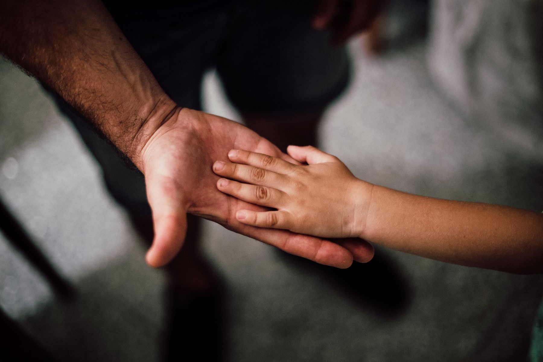 La mano abierta de un adulto y encima, apoyada, la mano pequeña de un niño