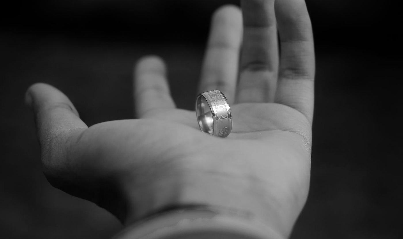 Una mano abierta sosteniendo un anillo de acero con la palabra Jesús grabada