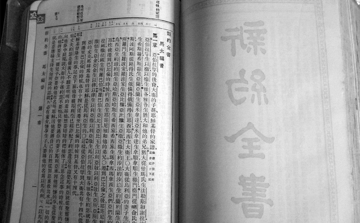 Una Biblia en chino, vieja y abierta, con el título del Nuevo Testamento en caracteres grandes