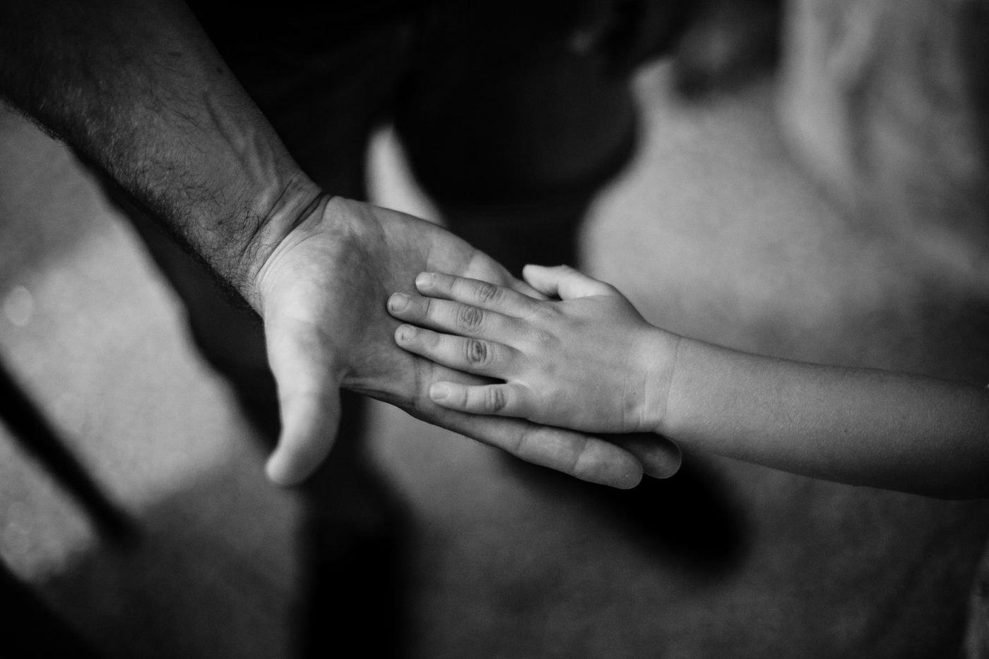 La mano abierta de un adulto y encima, apoyada, la mano pequeña de un niño