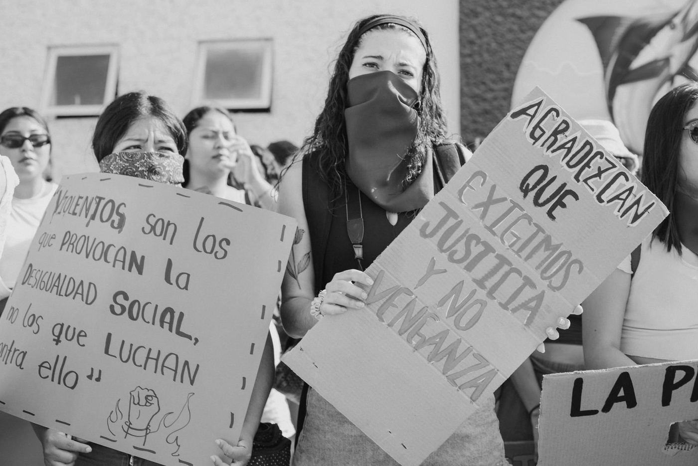 Jóvenes en una marcha sosteniendo carteles de cartón escritos a mano