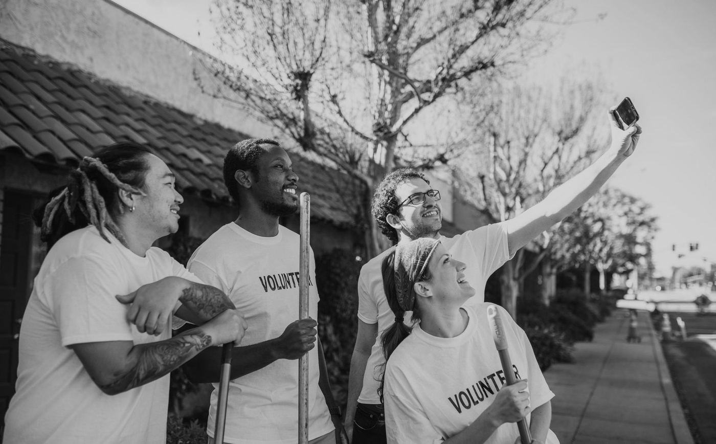 Cuatro voluntarios con camisetas blancas iguales se toman una selfie en la calle
