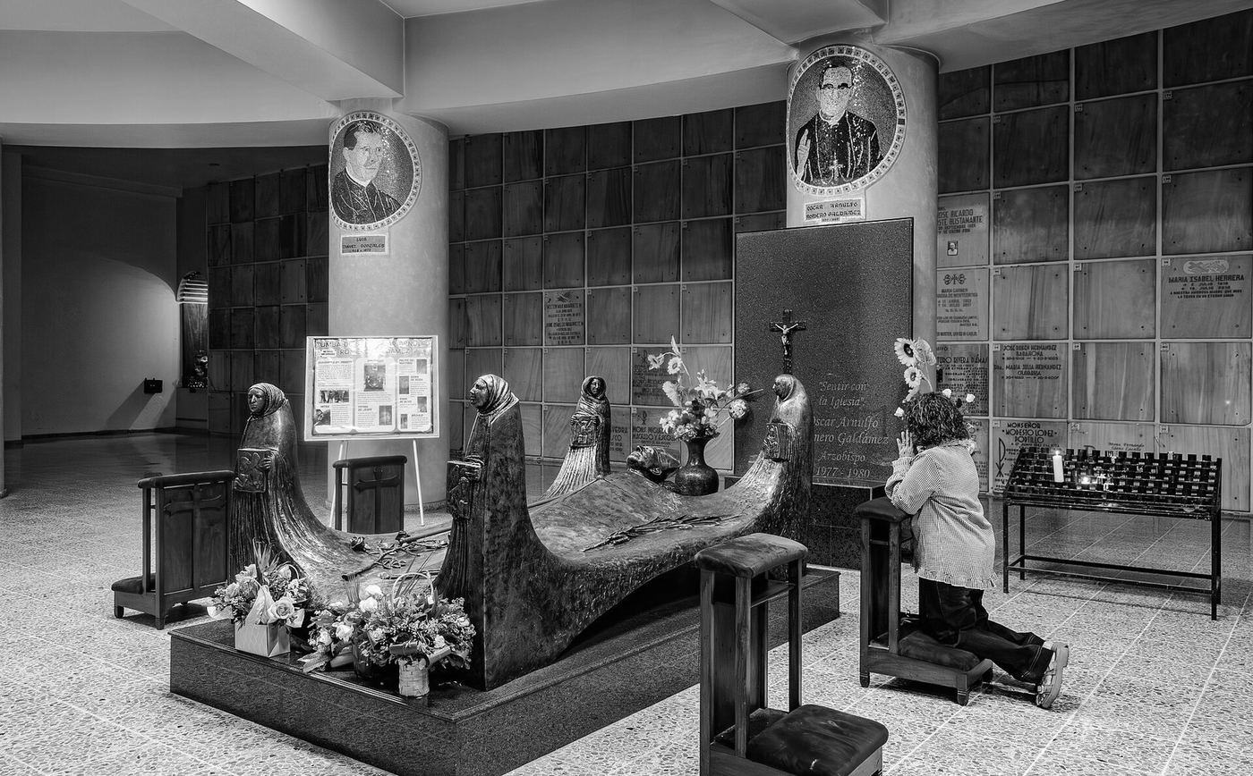 Una mujer reza frente a la tumba de san Óscar Romero, en la cripta de la catedral metropolitana de San Salvador