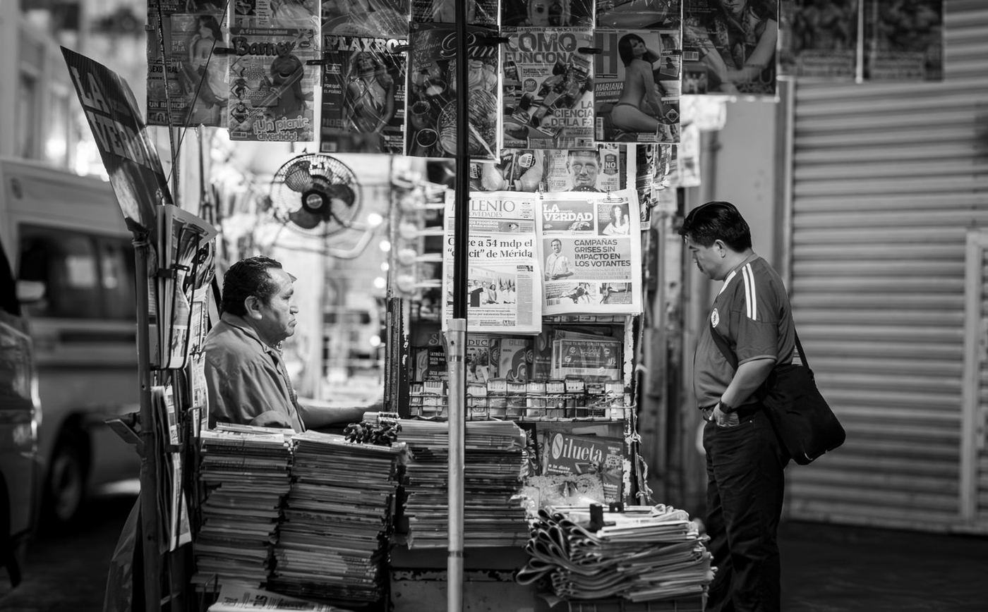 Un puesto de periódicos y revistas en una calle de Mérida, en México, con un hombre leyendo los titulares